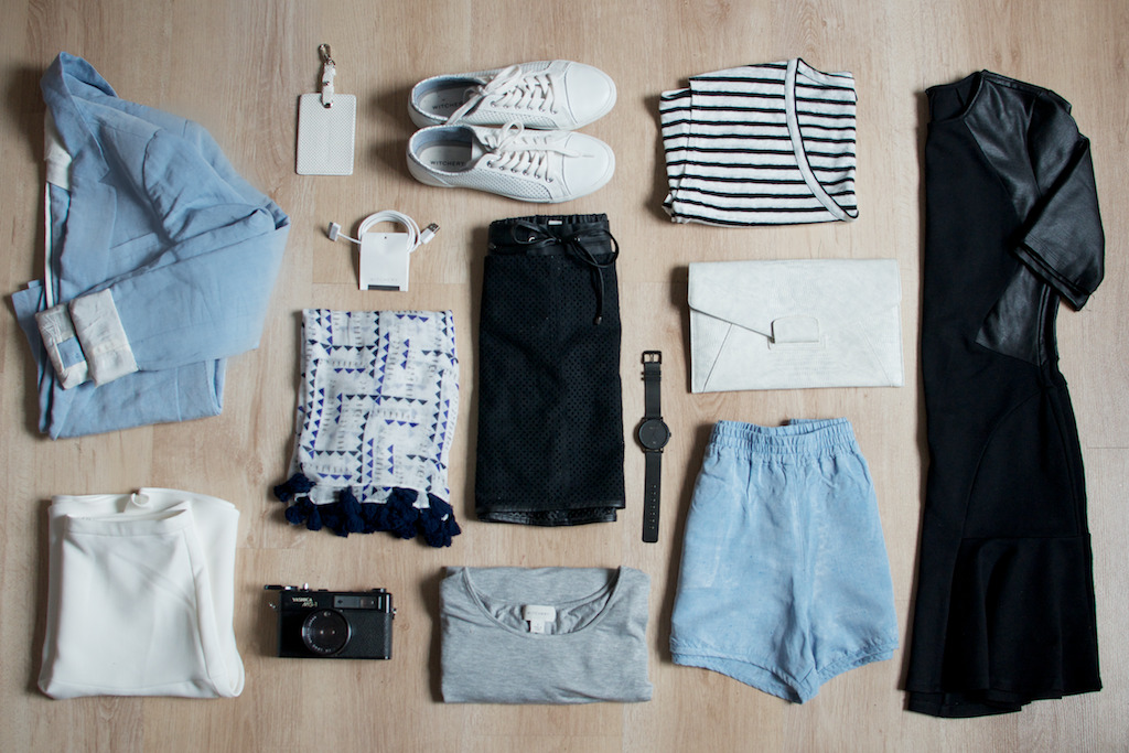 A collection of clothes and accessories laid out on a wooden floor.