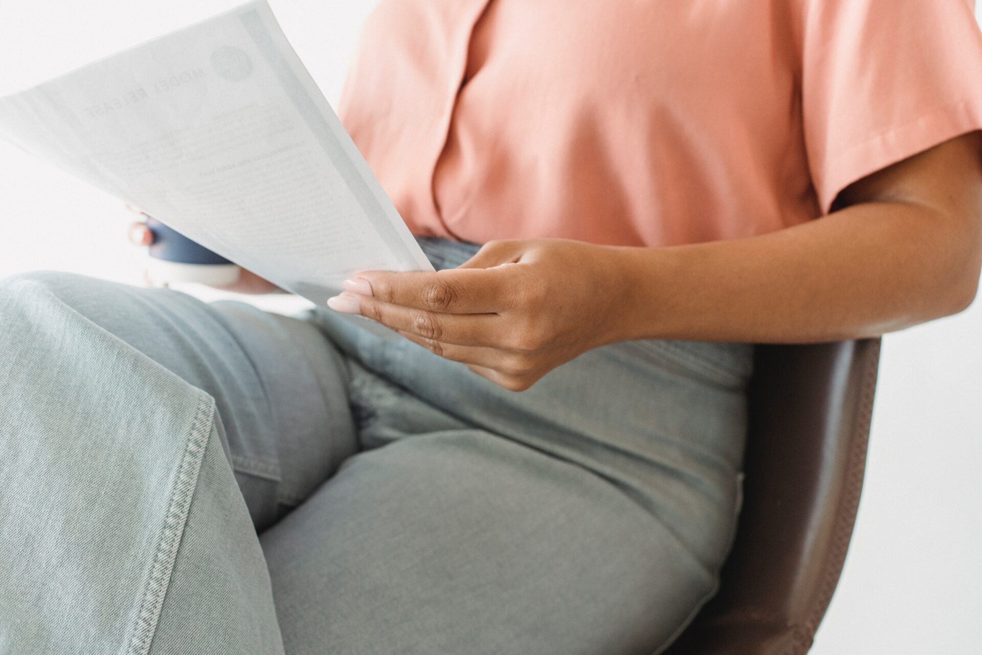 A woman sitting in a chair reading a newspaper.