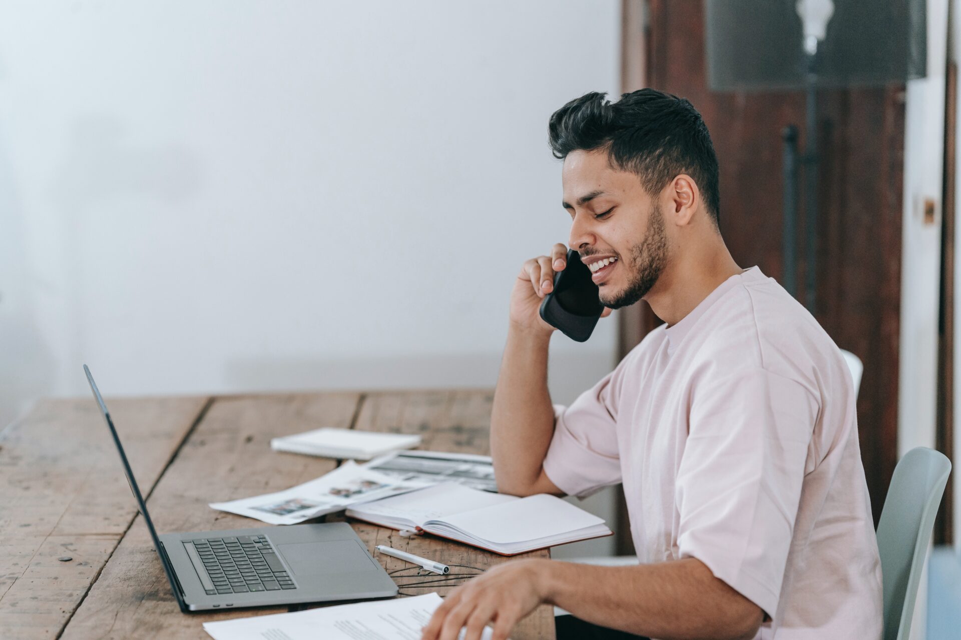 A man is talking on the phone while sitting at a desk.