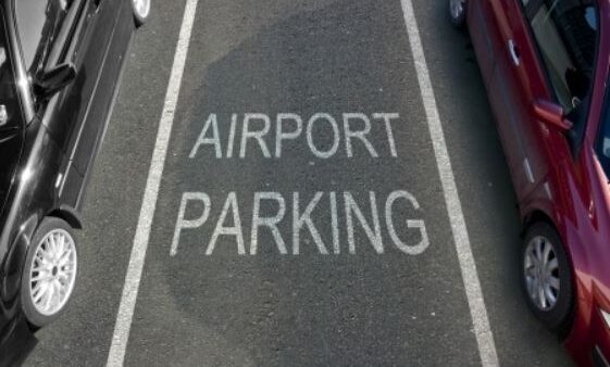 Two cars parked on a road with the word airport parking written on it.