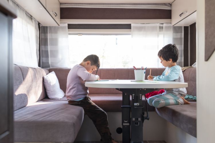 Two children sitting at a table in an rv.