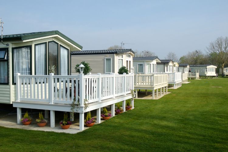 A row of mobile homes in a grassy area.