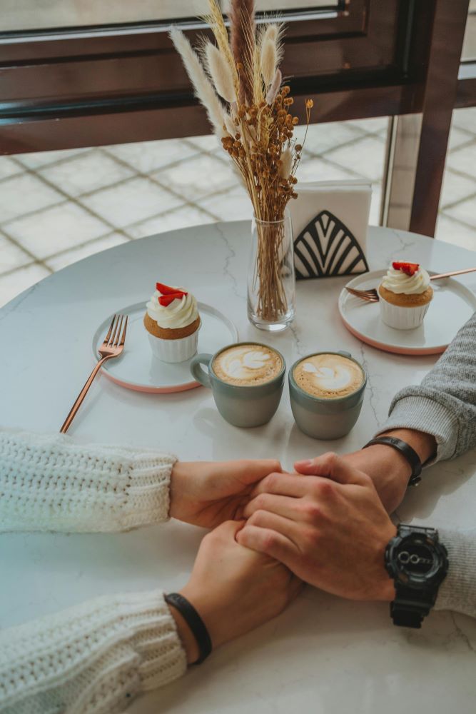 Two people holding hands at a table in a cafe.
