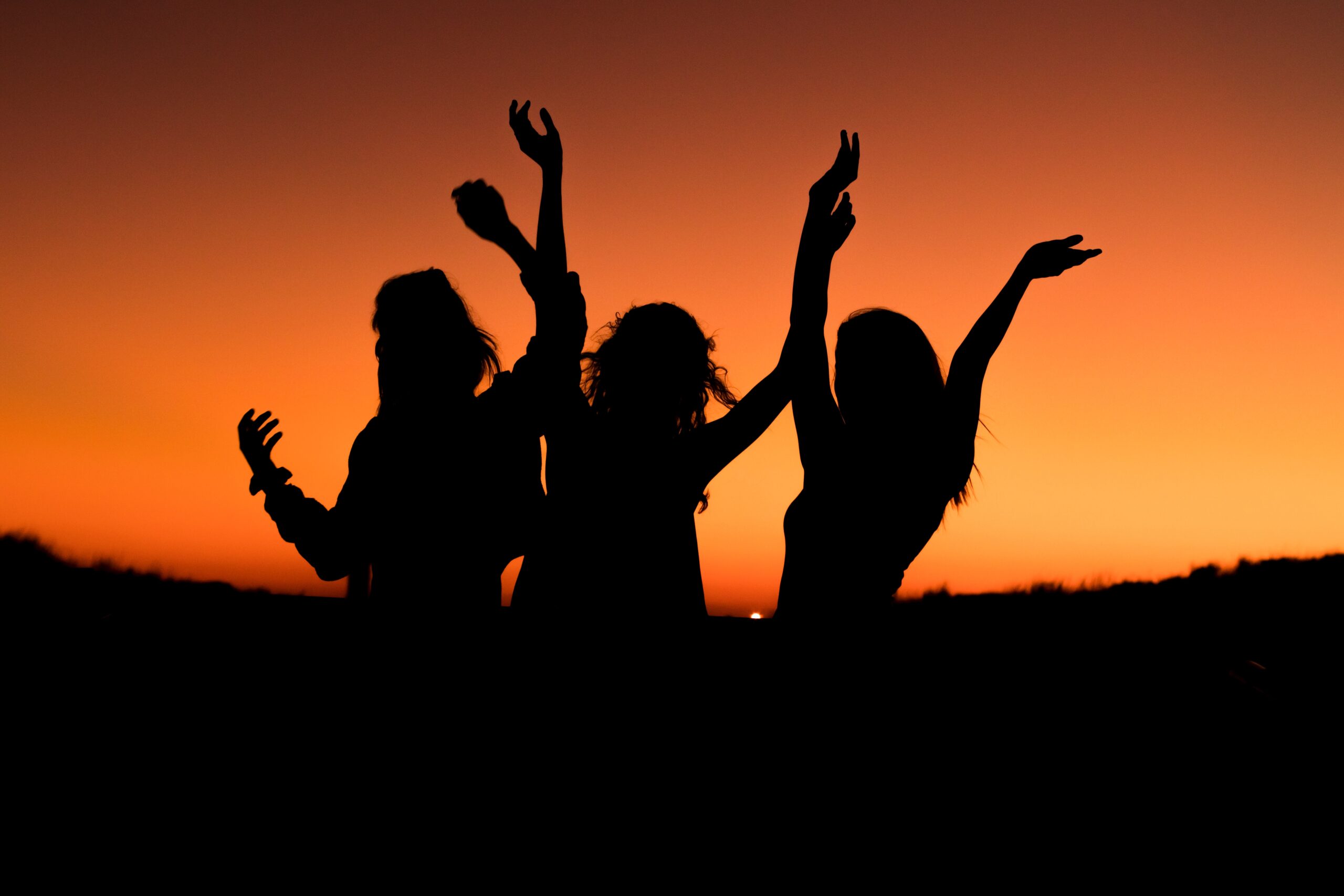 Silhouette of a group of people engaged in hen party activities at sunset.