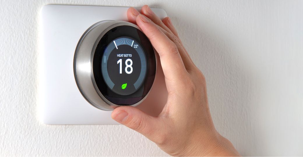 A person holding a nest thermostat.