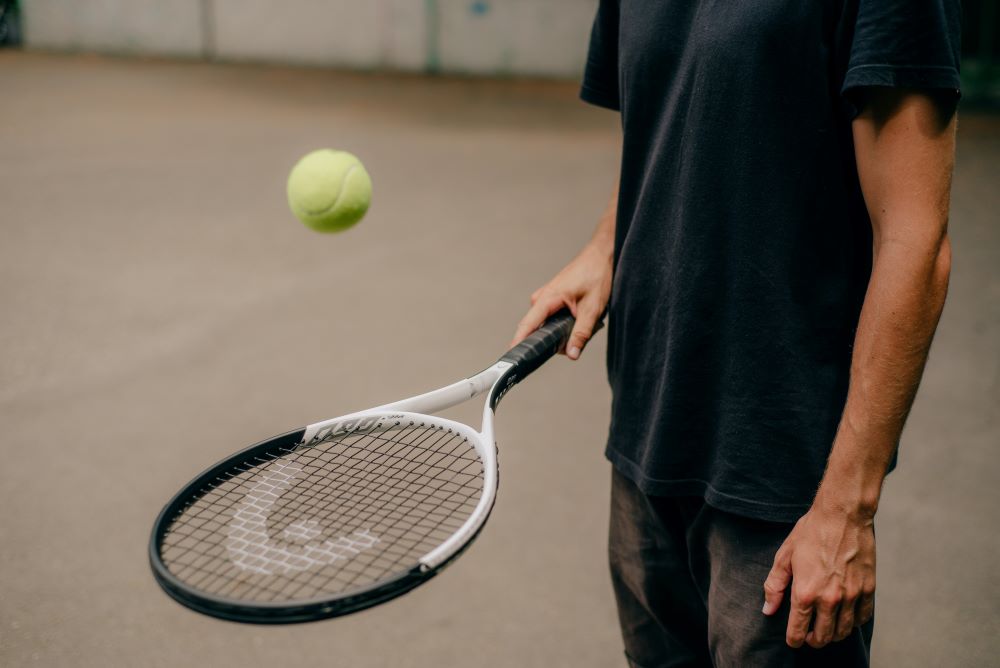 A man holding a tennis racket and a tennis ball.