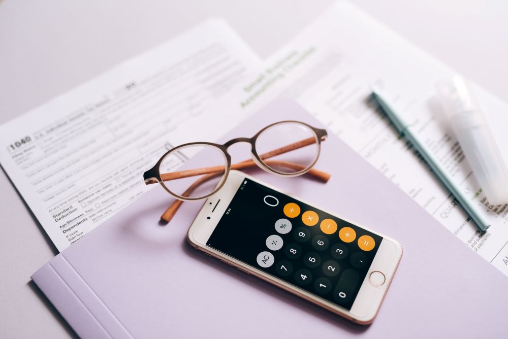 A calculator and glasses on a desk next to a tax form, illustrating stamp duty thresholds and relief options for first-time buyers.