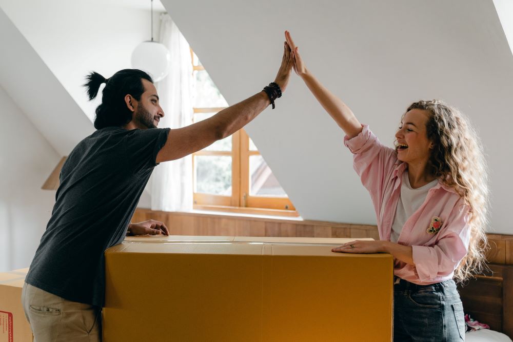 Young couple giving each other a high five as first-time buyers moving into a new home, feeling relief from the stamp duty thresholds.