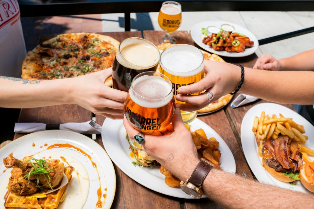 A group of people toasting at a table with food and beer.