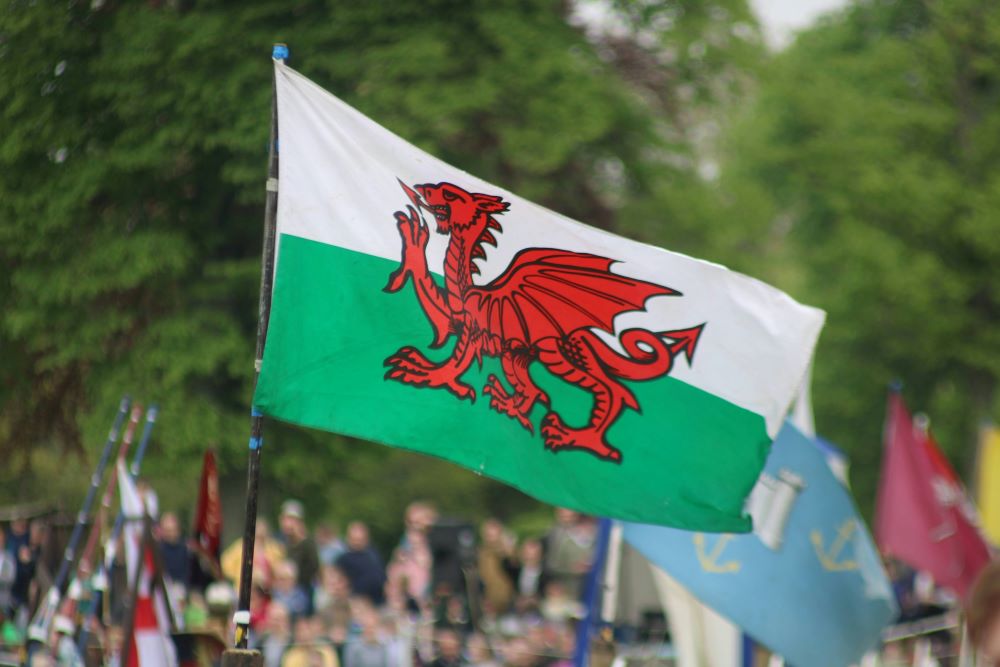 A large wales flag is fluttering in the wind.