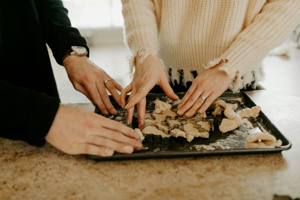 Couple making dumplings on a baking sheet.