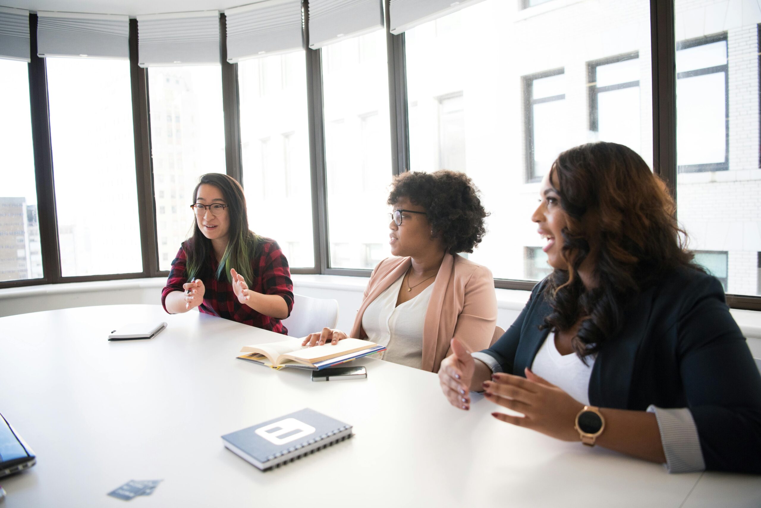 A group of women participating in a paid focus group, earning extra money, while sitting around a conference table.