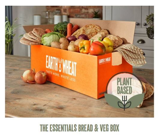 earth and wheat bread box 2 Open box of assorted breads and vegetables from Earth & Wheat, labeled "Plant Based," with onions on the side.