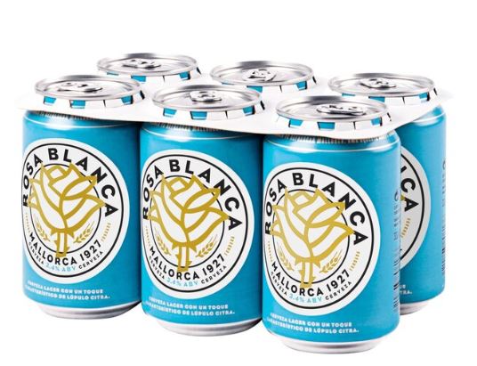 A six-pack of Rosa Blanca Mallorca 1927 lager beer cans with blue and gold labels, held together by a white plastic carrier.