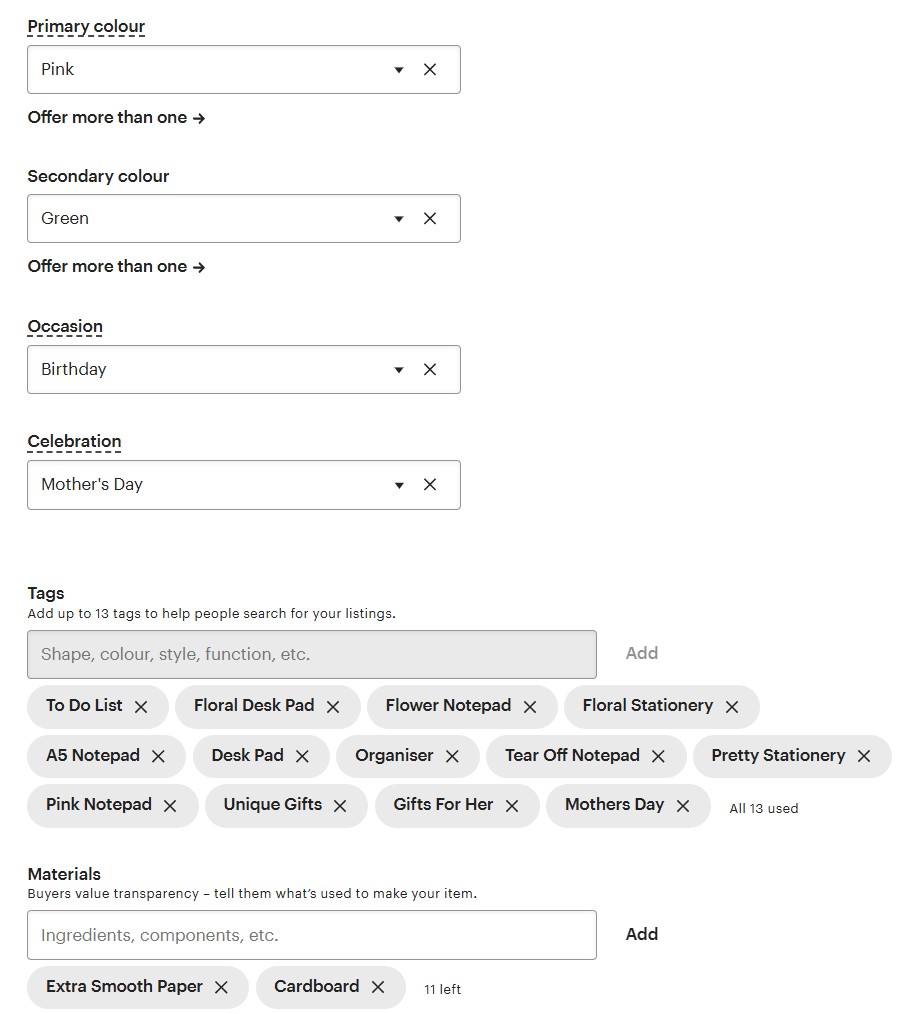 A product listing form with dropdown menus for primary and secondary color, occasion, and celebration; tags and materials fields are filled with various stationery-related keywords.