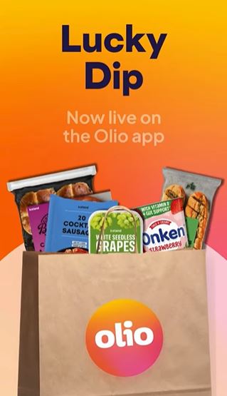 A paper bag with the Olio logo contains assorted groceries, including grapes, sausages, granola bars, and yogurt. Text above reads: "Lucky Dip. Now live on the Olio app.