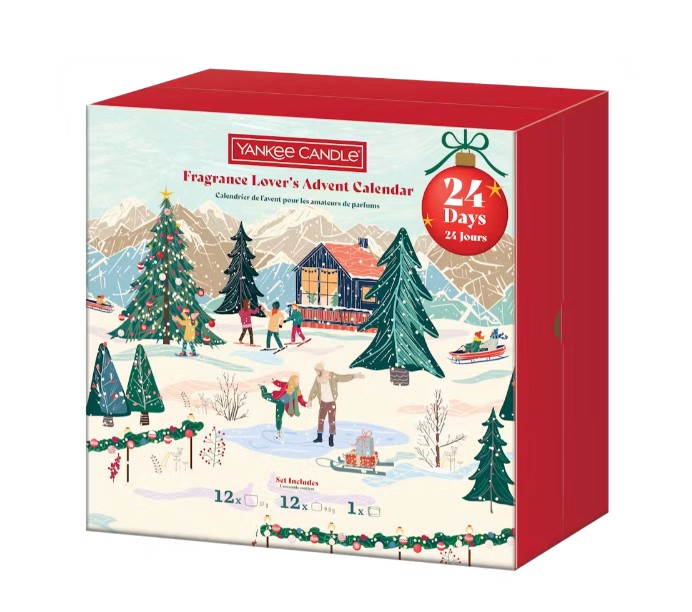 A red Yankee Candle Fragrance Lover's Advent Calendar box featuring a festive winter scene with people, trees, snow, and a house; text notes 24 days of surprises.
