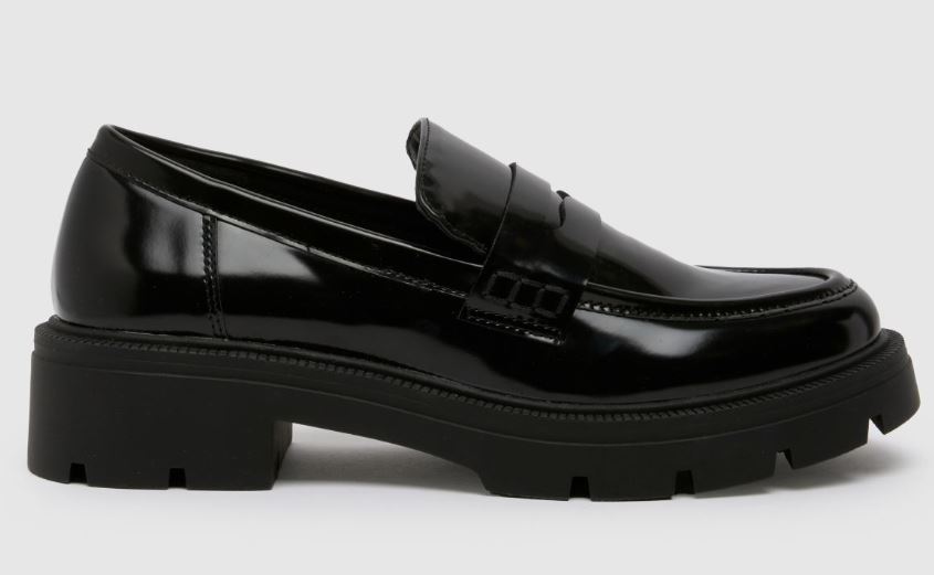 A black, shiny leather loafer with a chunky rubber sole and a low heel, photographed from the side on a plain background.