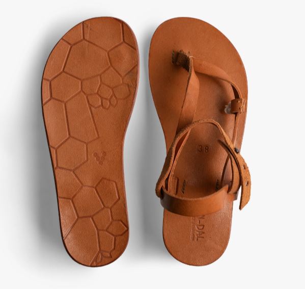 A pair of brown leather sandals shown from above and below; the sole features a hexagonal pattern and the upper has simple straps.