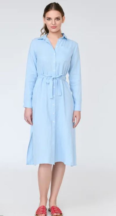 A woman stands facing forward wearing a light blue, long-sleeve, button-down midi dress with a matching waist tie and red slip-on shoes.