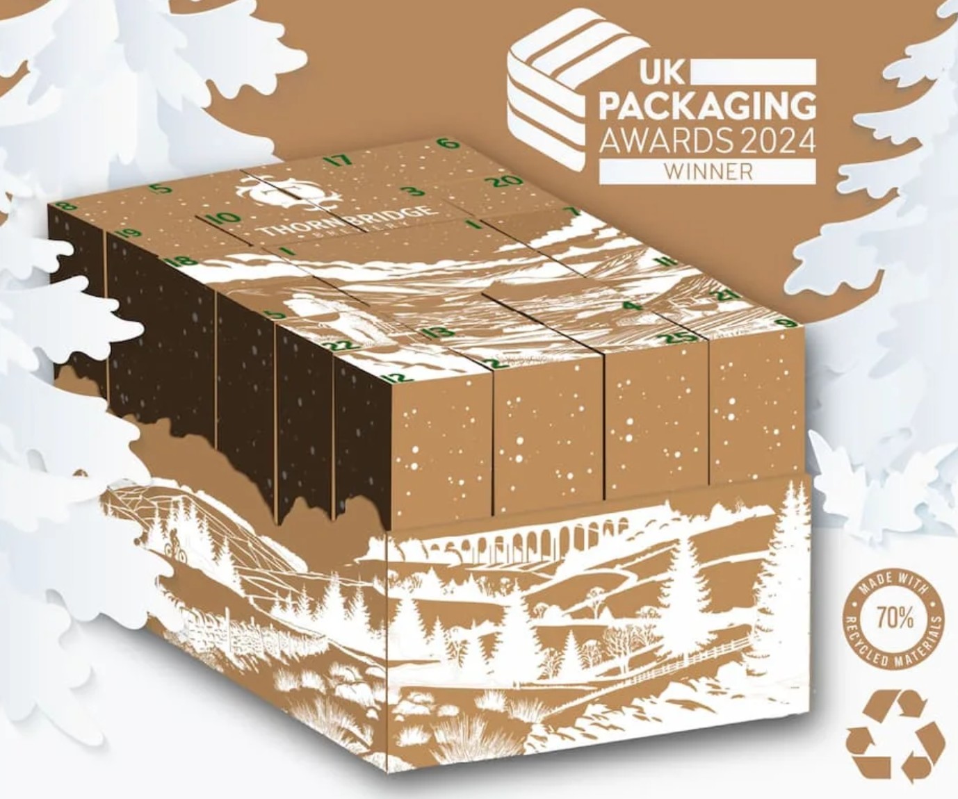 Illustration of a cube-shaped advent calendar box with winter scenery, trees, and viaduct, labeled as a 2024 UK Packaging Awards winner and “made with 70% recycled material.”.