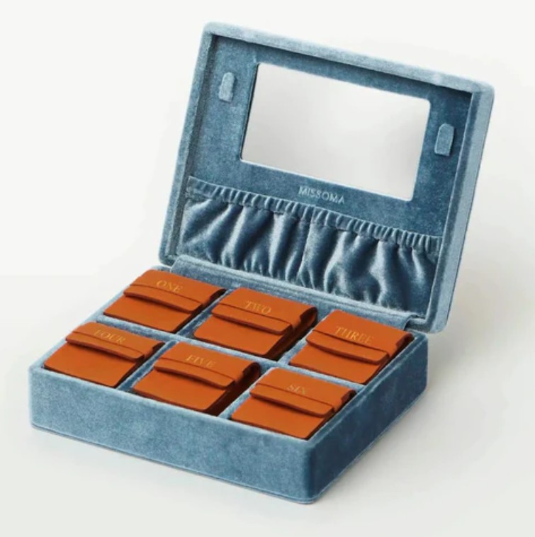 Missoma Fine Jewellery Advent Calendar 2025 A blue velvet jewelry organizer with a mirror, six brown pouches labeled one to six, and a ruched pocket inside the lid.