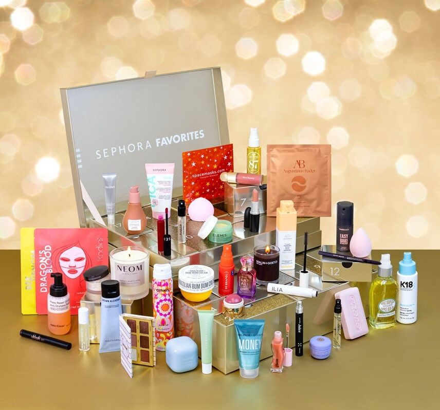 A display of assorted beauty and skincare products in front of a Sephora Favorites box, arranged on clear stands with a gold and bokeh background.