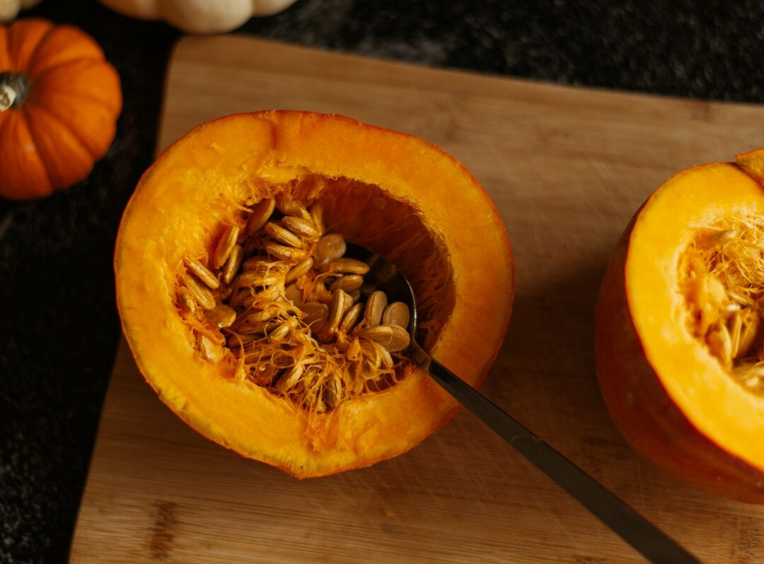 Photo by Yuliia Huzenko a couple of pumpkins sitting on top of a wooden cutting board