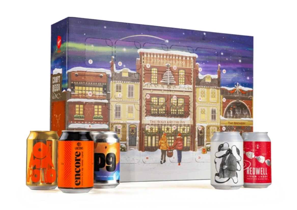 Advent calendar box with an illustrated winter street scene in the background and five assorted craft beer cans displayed in front.