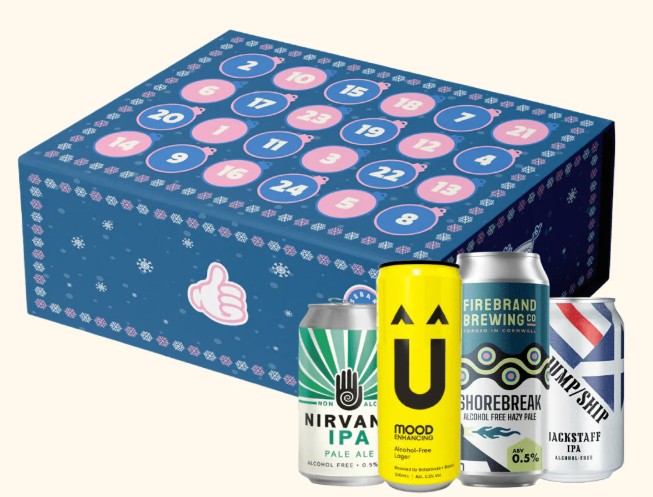 A blue advent calendar box with numbered doors is shown behind four cans of non-alcoholic beer from different brands.
