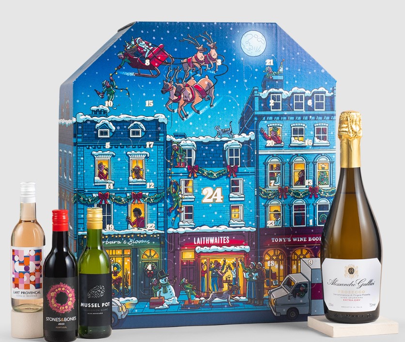 Advent calendar box with a festive cityscape scene, four bottles of wine, and one bottle of sparkling wine arranged beside it.