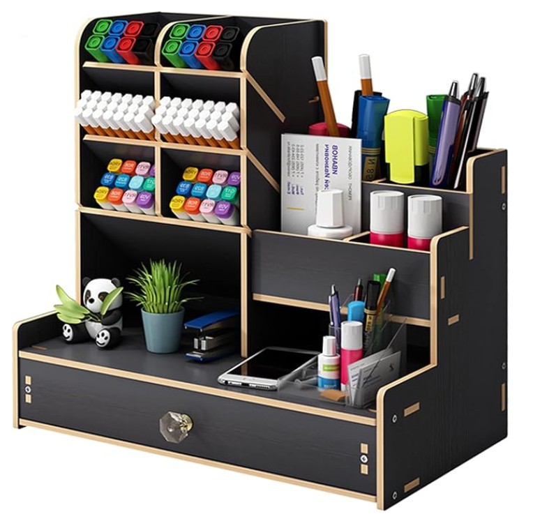 A black wooden desk organizer holding markers, pens, sticky notes, glue sticks, scissors, a plant, a panda figurine, and a phone, with a drawer at the bottom.