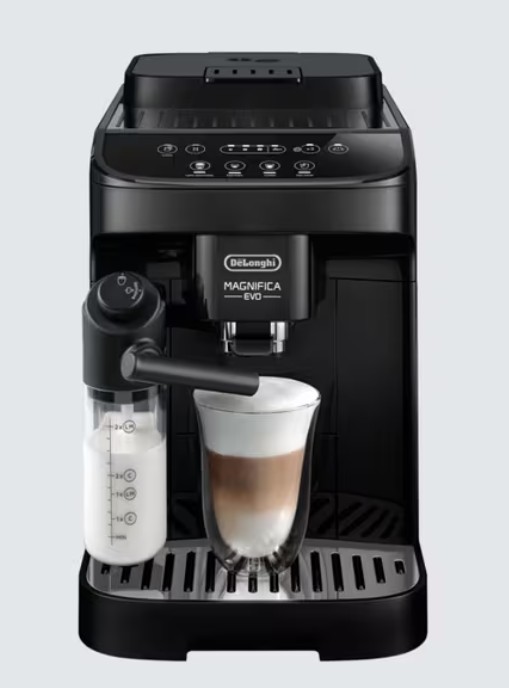A DeLonghi Magnifica Evo espresso machine making a layered coffee drink, with a milk frother attached and a clear glass cup beneath the dispenser.