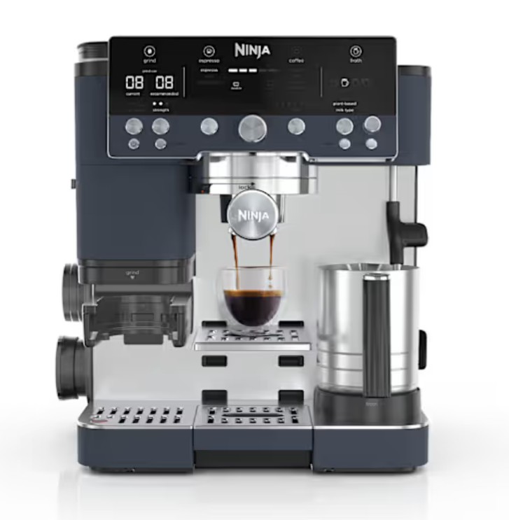 A Ninja espresso machine dispensing coffee into a clear glass cup, with milk frother and bean grinder attachments visible.