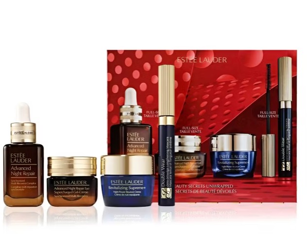 A set of Estée Lauder skincare and makeup products, including serums, creams, and mascaras, displayed in front of a red gift box.