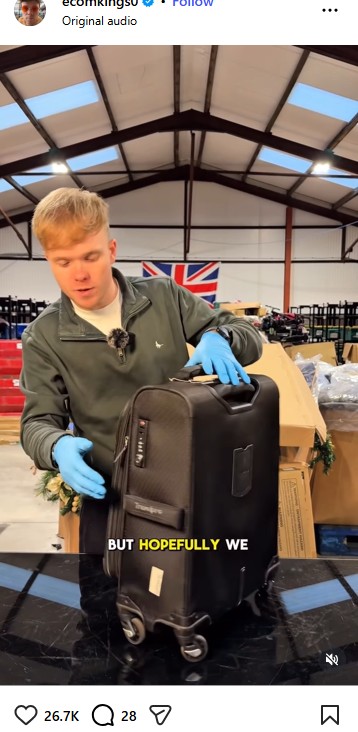 A person wearing blue gloves stands behind a black suitcase in a warehouse-like setting, with a large Union Jack flag on the wall in the background. Text on image reads, "BUT HOPEFULLY WE.