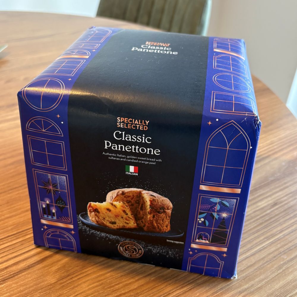 aldi specially selected classic panettone A box of Specially Selected Classic Panettone sits on a wooden table, featuring decorative blue packaging with images of windows and a sliced panettone on the front.