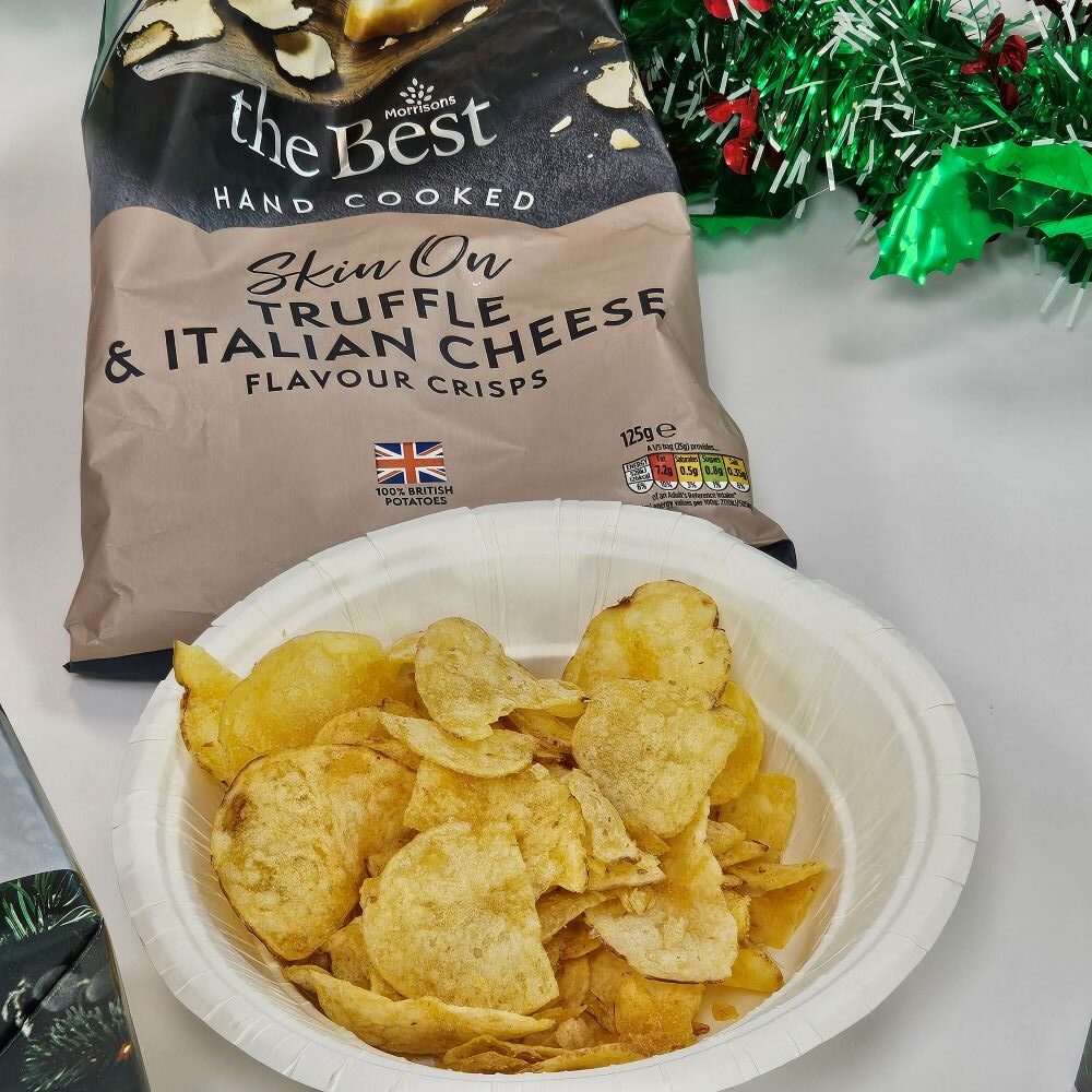 tcb morrisons the best truffle and parmesan handcooked crisps A bowl of truffle and Italian cheese flavor crisps sits in front of the opened bag, with Christmas decorations visible in the background.