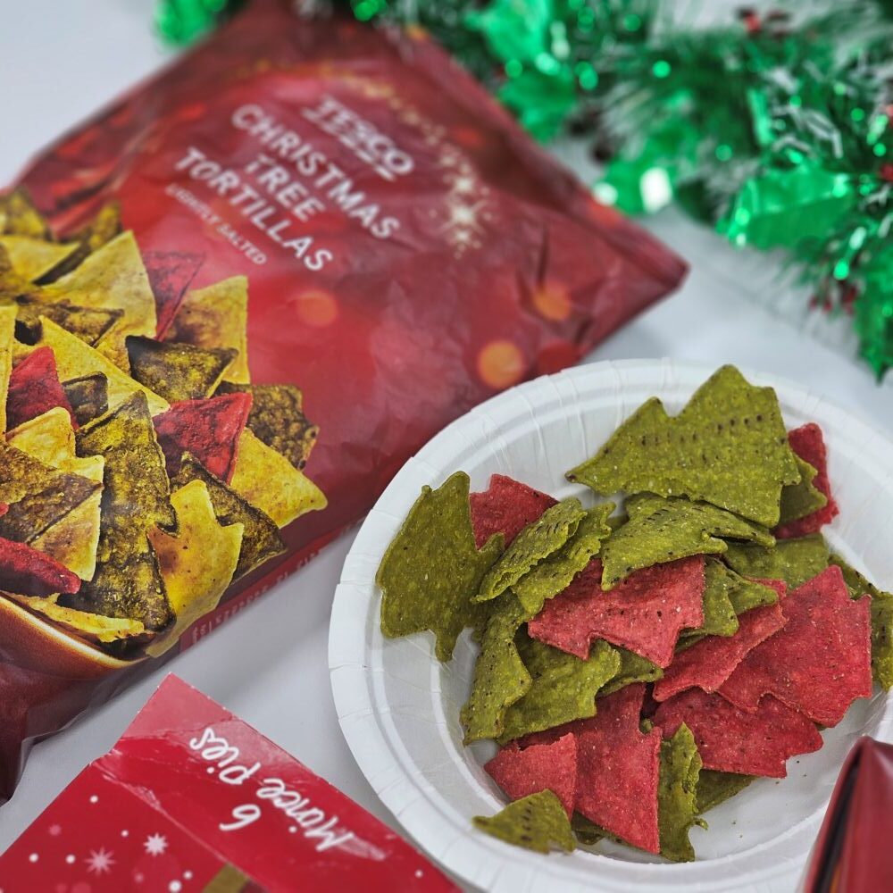 tcb tesco christmas tree tortillas A plate of red and green Christmas tree-shaped tortilla chips next to an open bag labeled "Christmas Tree Tortillas" and festive decorations.