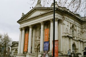 The facade of Tate Britain museum with columns, statues, and banners displaying exhibition information and the words 