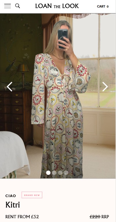 loan the look mobile Woman taking a mirror selfie in a bedroom, wearing a long, patterned dress with circular designs. The view outside shows trees and a lawn.