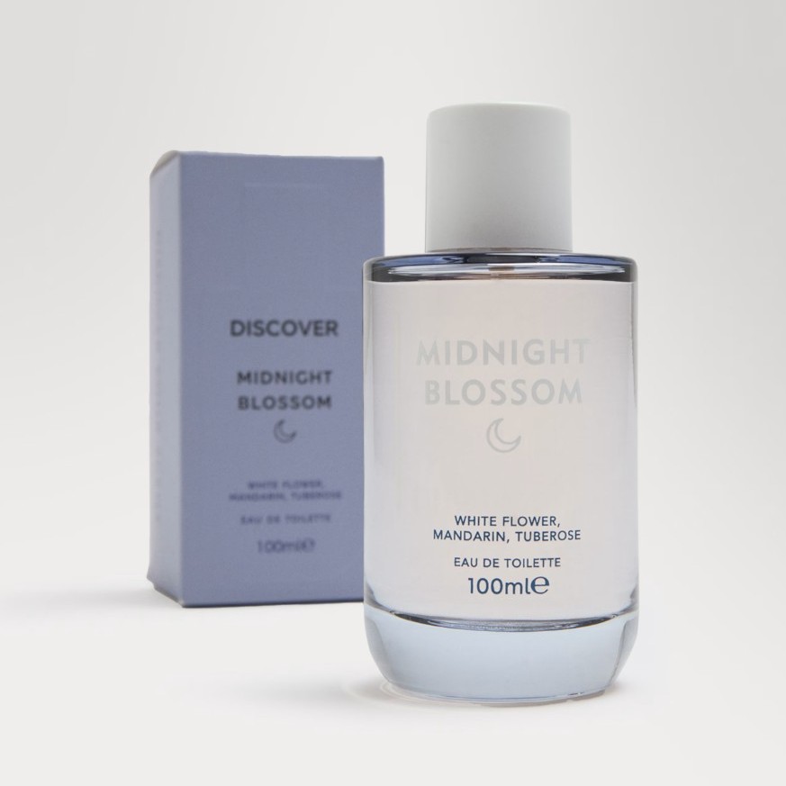 A 100ml bottle of "Midnight Blossom" eau de toilette is shown in front of its purple box packaging. The label lists white flower, mandarin, and tuberose as notes.