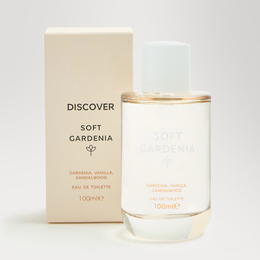 A clear glass bottle labeled “Soft Gardenia” sits beside its beige box packaging. The fragrance notes are gardenia, vanilla, and sandalwood. The bottle contains 100ml.