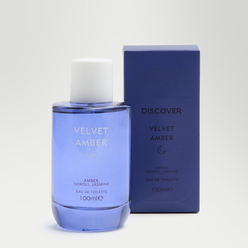 A blue bottle of Velvet Amber eau de toilette is placed next to its matching blue box, both labeled with the fragrance name and scent notes: amber, neroli, jasmine.