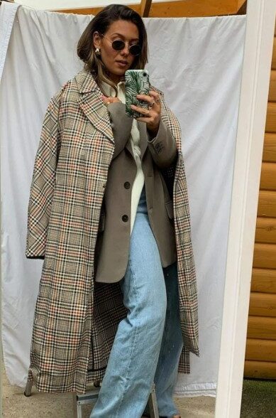 trench coat french connection Woman taking a mirror selfie wears sunglasses, a plaid overcoat over a beige blazer, light blue jeans, and light-colored sandals, standing on a small step stool.