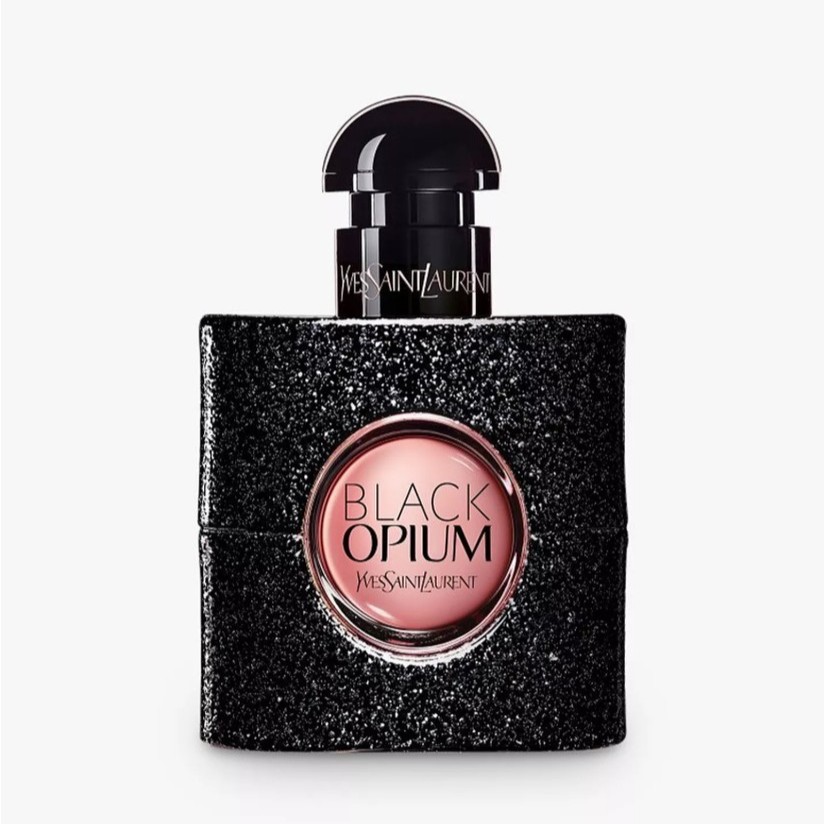 A bottle of Yves Saint Laurent Black Opium perfume with a glittery black finish and a round, pink center label.