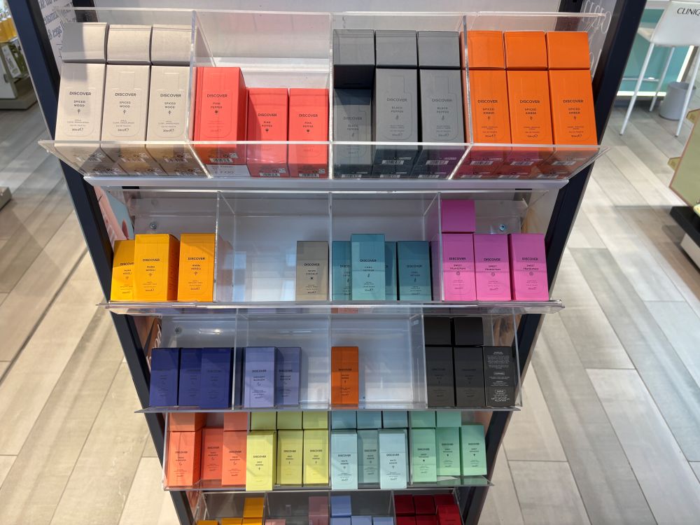 Shelves display rows of colorful skincare product boxes arranged by color and type in a retail store.