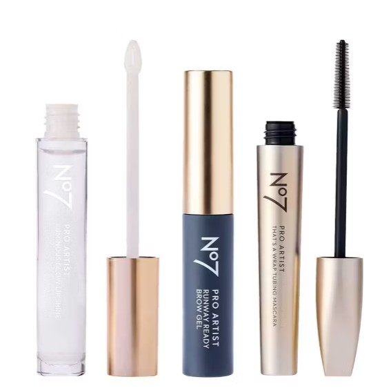 Three No7 Pro Artist makeup products shown upright: a clear brow shaper, a brow gel with brush, and a black mascara with wand, all with gold or gold-accented caps.