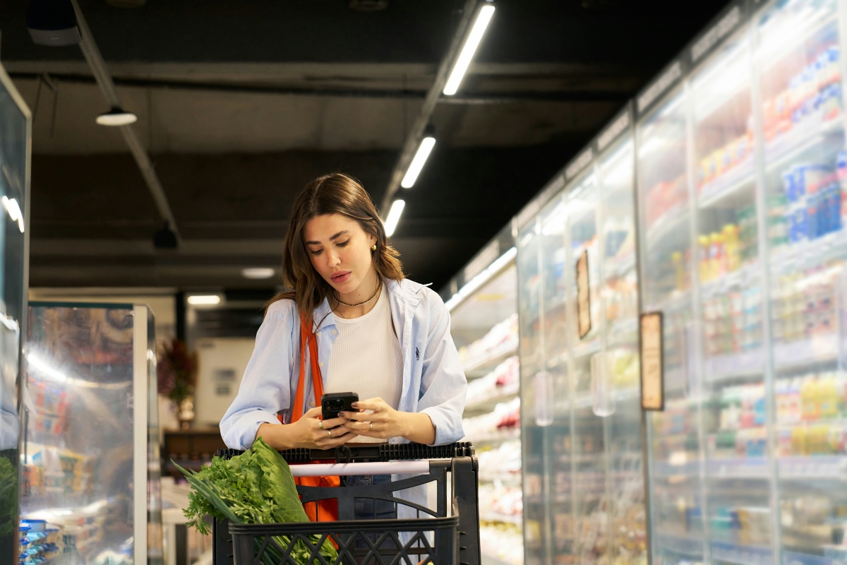 dine in shopping A woman standing by her shopping cart, reading her shopping list for supermarket dine-in deals