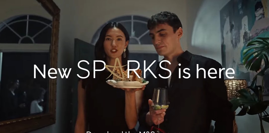 new sparks image A woman holding a plate of food stands next to a man holding a drink at a party. Text overlay reads, "New SPARKS is here.
